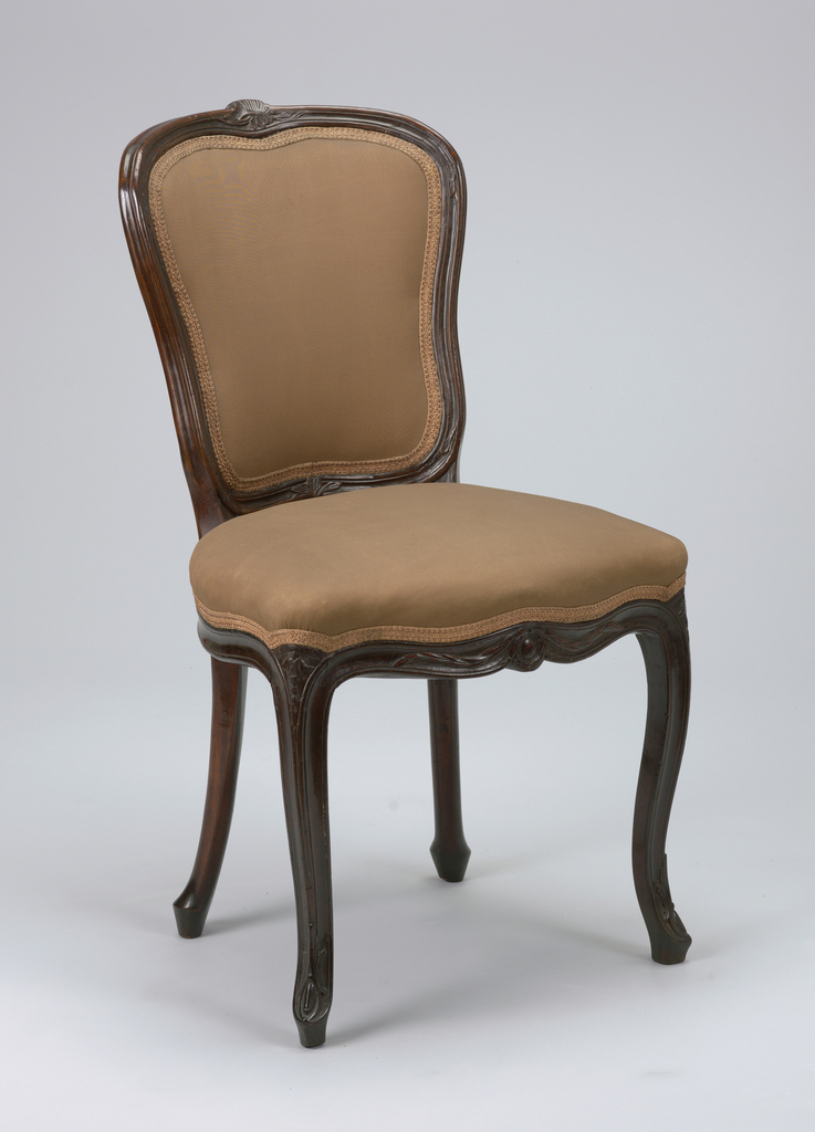 A mahogany chair with carved foliage designs on the frame and elegantly curved legs. The rounded back and seat are upholstered in brown fabric with a matching braid trim at the edges.