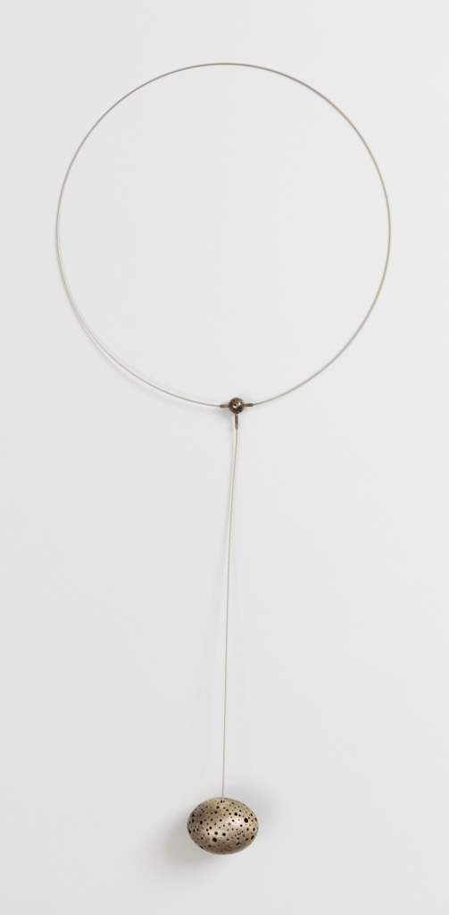 A thin silver circlet attached with a perforated three prong bronze colored circle. A thin string hangs, at the end is a perforated medium sized orb shaped like an egg.