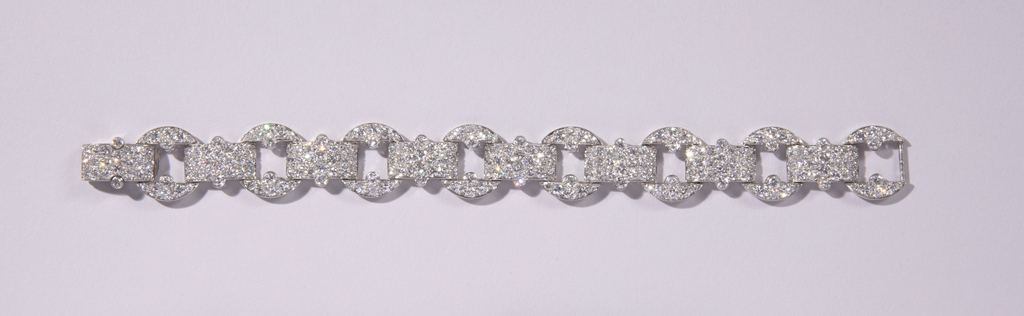 This is a link bracelet of diamonds and platinum. Each of the seven pave circles is linked to the other by a pave diamond bar. The clasp is one of the bars.