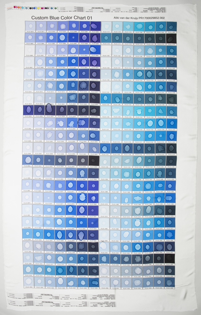 A custom blue color chart on silk from Pantone in a grid pattern with water stains in each center. Each square is a different shade of blue, including white to black saturation. Color signifiers are finely printed at the top and base of the silk, above the colored grids.