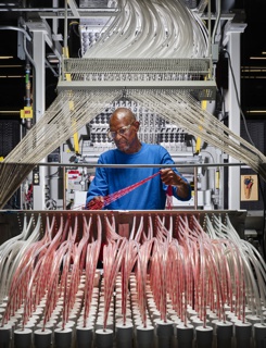 Photograph, Gary L. Boddie gathering yarn to be fed into a carpet tufter