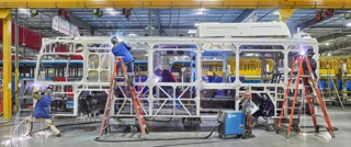 Photograph, Welders adding parts to the steel frame of an electric public transit bus