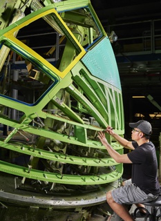 Photograph, Daniel Ly locating fasterner holes on the nose of a Boeing 767 in preparation for installation of aluminum panels that become the skin of the aircraft