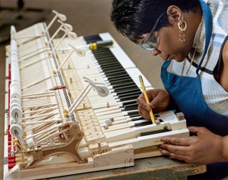 Photograph, Gwendolyn Folk inserts lead weights into the keys to ensure balanced action