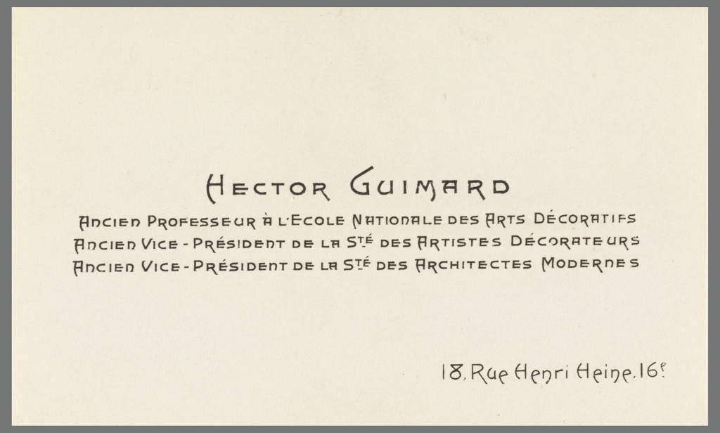 A beige business card on a dark grey background printed in a bold Art Nouveau font with the name Hector Guimard in the center, centered below that in a slightly smaller size is printed “ANCIEN PROFESSEUR À L'ECOLE NATIONALE DES ARTS DÉCORATIFS / ANCIEN VICE-PRÉSIDENT DE LA STÉ DES ARTISTES DÉCORATEURS / ANCIEN VICE-PRÉSIDENT DE LA STÉ DES ARCHITECTES MODERNES” which translates in English to Former Teacher at the National School of Decorative Arts / Former Vice-President of The Store of Decorative Artists / Former Vice-President of The Stage of Modern Architects. Below in the lower right is the address 18, Rue Henri Henri, 16p printed in a different Art Nouveau style font