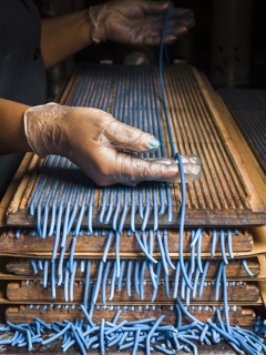 Photograph, Maria Severino laying extruded pastel cores for colored pencils onto grooved wooden boards to dry