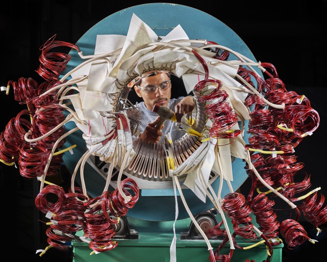 Photograph, Daniel Anzures assembling a heavy industrial motor