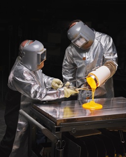 Photograph, Engineers pouring molten glass onto a stainless-steel tabletop to cool so it can be cut into pieces for testing