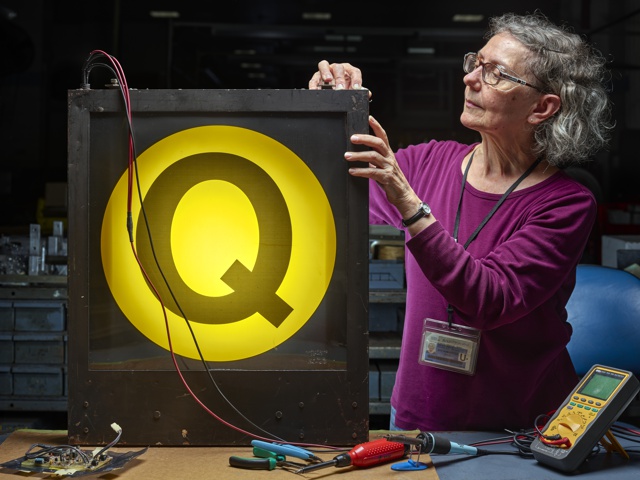 Photograph, Gay Burdick repairing an end destination sign in a lightbox at the 207th Street Overhaul Shop