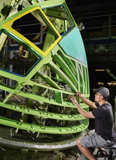 Photograph, Daniel Ly locating fasterner holes on the nose of a Boeing 767 in preparation for installation of aluminum panels that become the skin of the aircraft