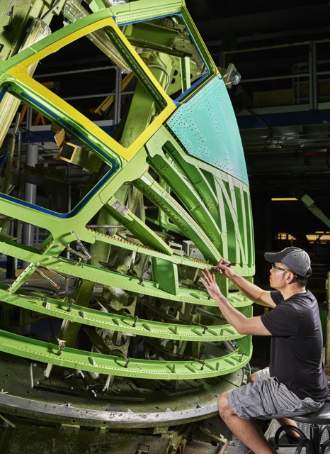 Photograph, Daniel Ly locating fasterner holes on the nose of a Boeing 767 in preparation for installation of aluminum panels that become the skin of the aircraft