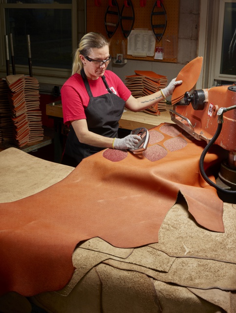 Photograph, Lindsey Kiene cutting leather panels to make an NFL football