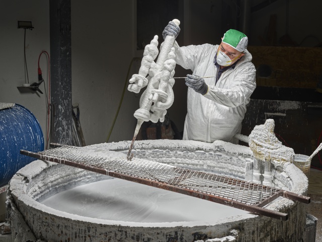Photograph, Jose Oliveros dipping wax Oscar® statuettes into vat of silica to create a ceramic mold for lost wax casting